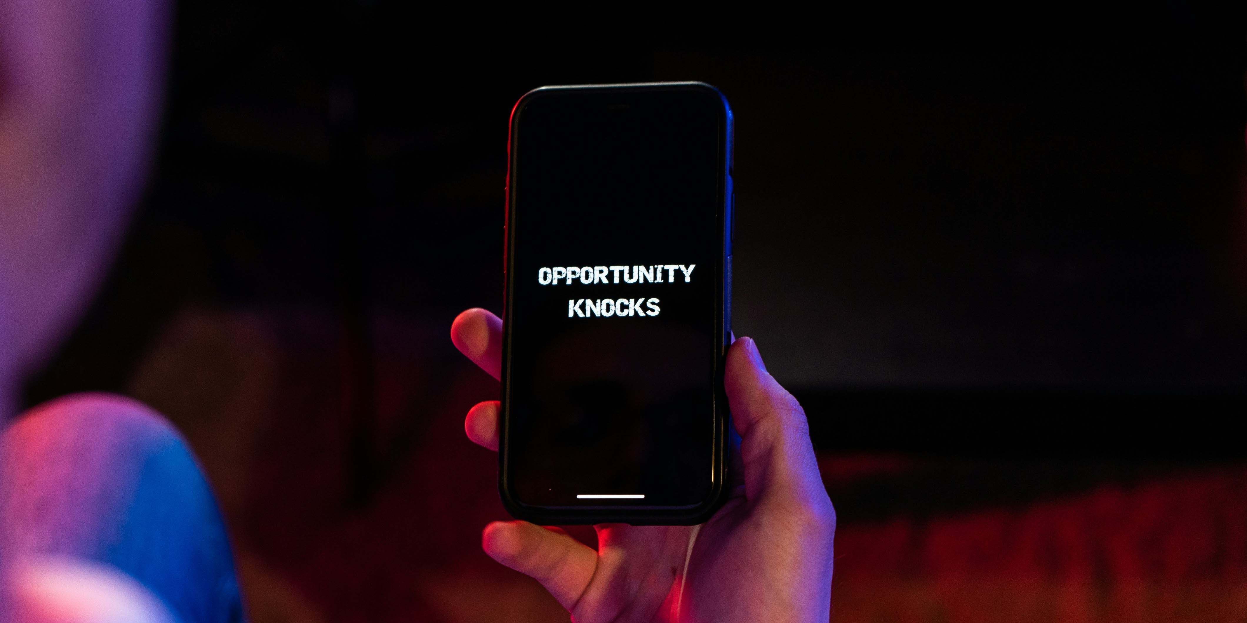 Auf dem Foto hält jemand sein Smartphone hoch. Auf dem Screen steht Opportunity knocks.