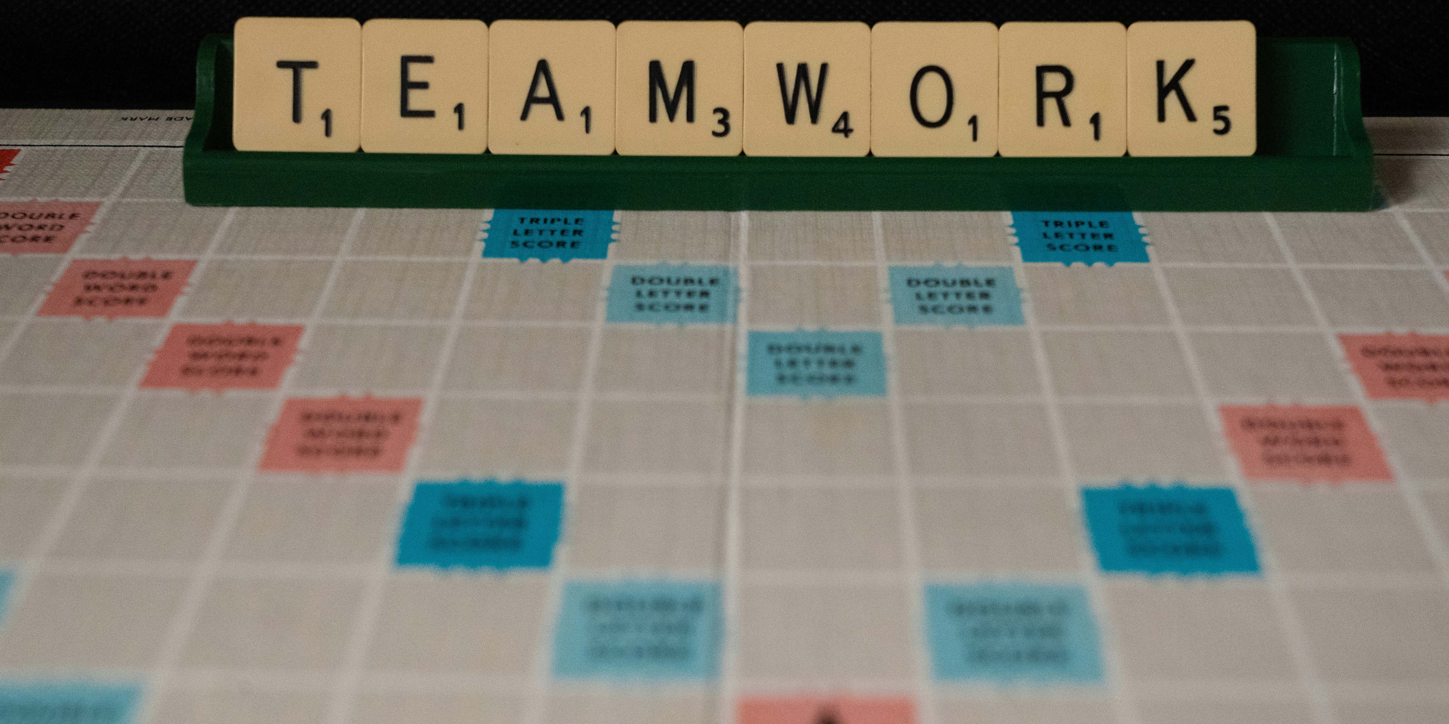 Auf dem Foto ist ein Scrabble Spielfeld zu sehen. Gelegt worden ist das Wort: Teamwork.