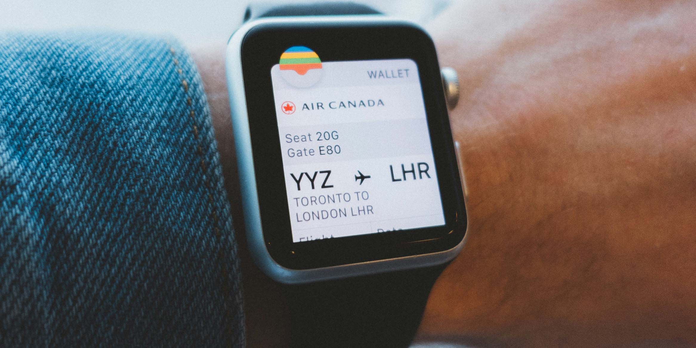 Auf dem Bild ist ein Handegelenk mit einer Smartwatch zu sehen. Auf dem Screen der Smartwatch ist ein Boardingpass zu sehen.