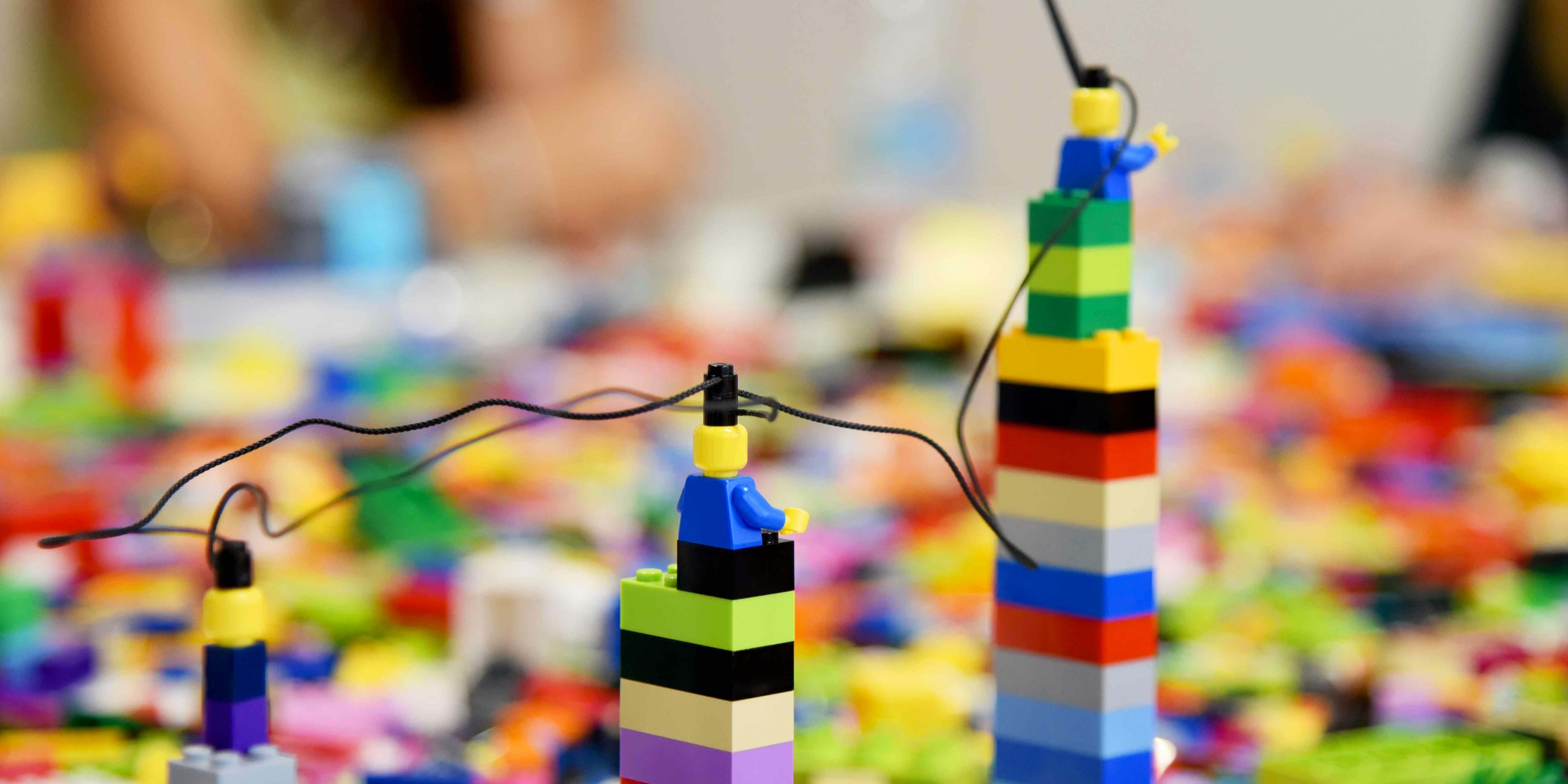 Auf dem Foto sind bunte Legosteine zu sehen und vorne sind drei unterschiedlich große Säulen gebaut.